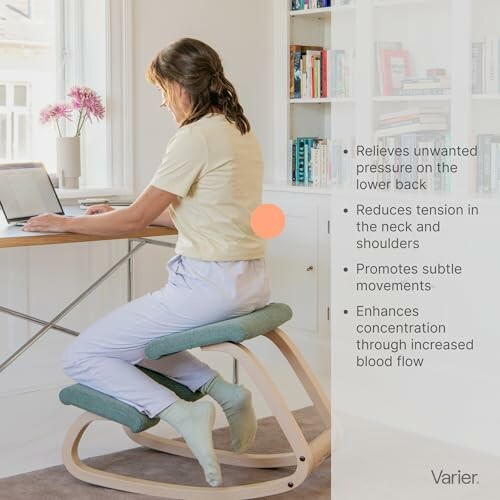 Person using an ergonomic kneeling chair while working on a laptop.