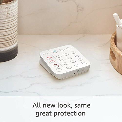 Home security keypad on a marble countertop with text 'All new look, same great protection'.