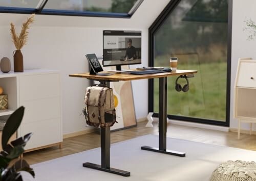 Stylish standing desk in a modern home office with a computer screen, coffee cup, and backpack.