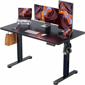 Modern standing desk with multiple screens, laptop, and accessories.