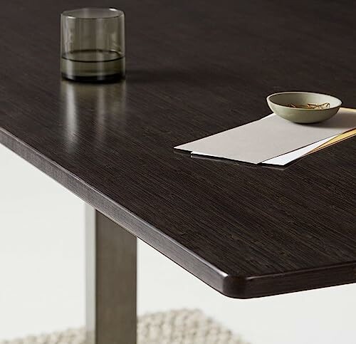 Dark wooden table with a glass, bowl, and papers