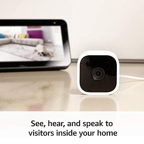 Smart home security camera on a table with a screen in the background